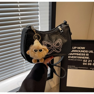 Détail du sac à main noir grainé avec broderie papillon et charm monstre en peluche
