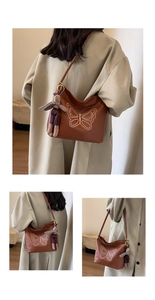 Detail of caramel leather tote bag with white butterfly embroidery and bunny charm