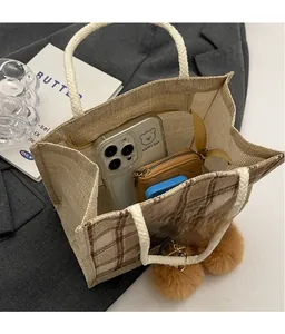 Detail view of plaid linen lunch bag interior with knotted rope handle and pom-poms