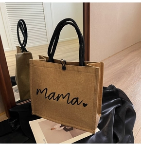 Detailed view of linen tote bag with mama print and black woven handles on silk