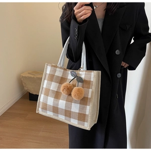 Detail of checkered linen tote bag featuring a decorative brown cherry plush charm