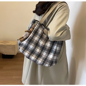 Close-up of wool plaid tote bag with FASHION leather tag and plush bear keychain