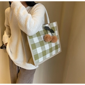 Close-up of green and white waffle pattern tote bag with decorative cherry pendant