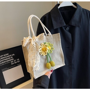 Detailed close-up of a rustic linen tote bag with delicate lace bow and knit flowers