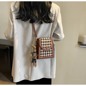 Detail of vintage crossbody bag with houndstooth pattern and cute rabbit charm