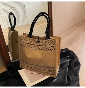 Detailed close-up of a jute tote bag with ethnic geometric patterns on black silk