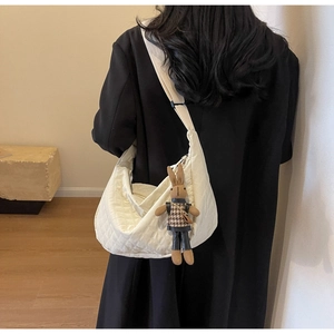 Vue détaillée d'un sac bandoulière matelassé beige avec un pendentif lapin mignon