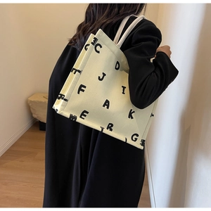 Model showing the large canvas tote bag with black letter print for daily commute