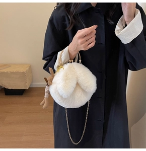 Detail of white faux fur rabbit ear bag with gold clasp and plush bunny charm
