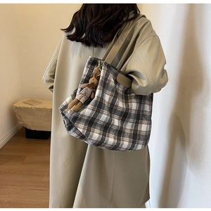 Detailed view of vintage plaid wool tote bag featuring a cute plush bunny charm accessory