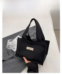 Détail du sac cabas en toile noire avec écusson FASHIONS BAG en situation de style de vie