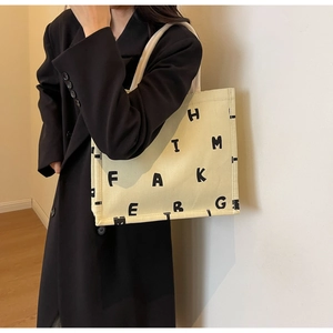 Detail of off-white canvas tote bag featuring artistic black letter print for daily use