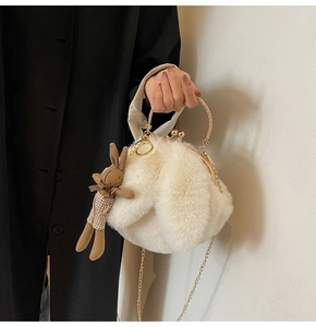 Detail of white faux fur handbag with golden ring handle and cute rabbit charm