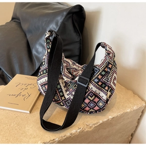 Close-up of bohemian geometric knit pattern and adjustable strap on half-moon bag
