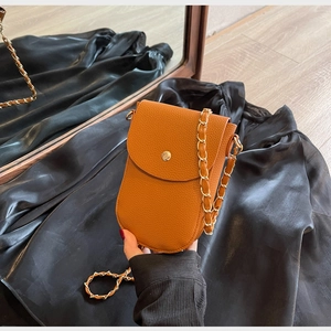 Detail der orangefarbenen Umhängetasche aus Leder mit goldener Kette und Schnalle