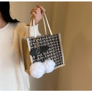 Detail of tweed woven tote bag with soft cotton handles and large faux fur cherry pendant