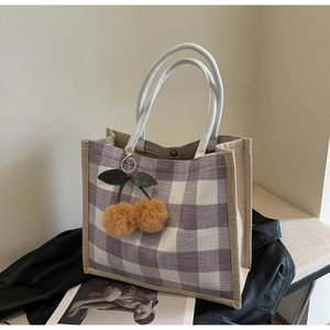 Detail of purple and white waffle weave tote bag with cherry pompom and rope handles