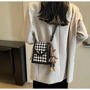 Close-up of checkerboard tweed crossbody bag with a cute brown bunny plush charm