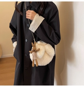 Detailed shot of white plush crossbody bag featuring golden chain and cute rabbit charm