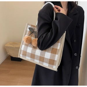 Detail of waffle plaid tote bag with braided rope handles and brown plush cherry charm