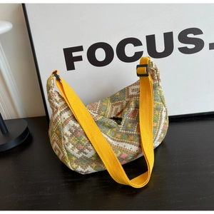 Detailed shot of ethnic woven dumpling bag with colorful geometric patterns and yellow strap
