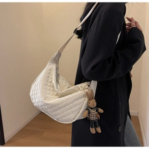 Détail du sac croissant matelassé blanc avec breloque lapin et bandoulière large sur modèle