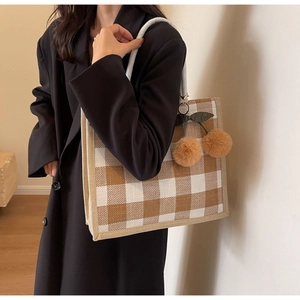 Detail of waffle-textured gingham tote bag featuring plush cherry-shaped hanging charms