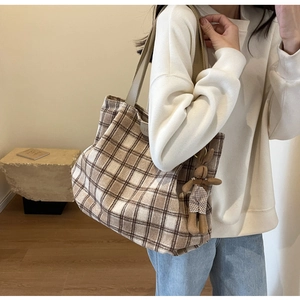 Close-up of a large brown plaid woolen tote bag with a cute plush bunny charm detail