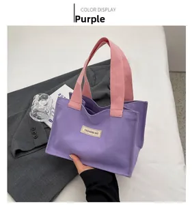Détail du sac cabas en toile violette avec anses roses sur un blazer pour la mode