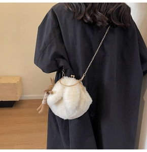 Detail of white plush rabbit crossbody bag with gold handle and metal chain strap