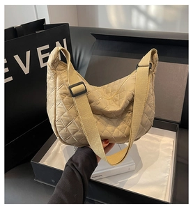 Detailed close-up of quilted rhombic half-moon crossbody bag in khaki with wide strap