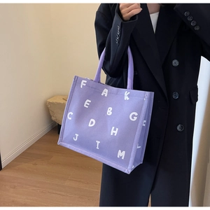 Detail of light purple canvas tote bag with white letters and black blazer styling