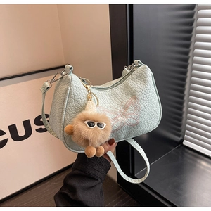 Détail du sac bleu clair à motif croco avec broderie papillon rose et breloque peluche
