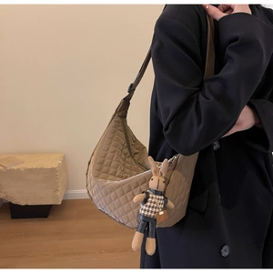 Détail d'un sac demi-lune marron matelassé avec pendentif lapin et large sangle