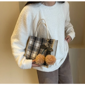 Detail of checkered tote bag with cherry charm and braided white rope handle