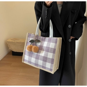 Detail of purple and white checkered linen tote bag with cherry pendant accessory
