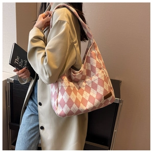 Detail view of pink argyle canvas tote bag with fashion leather tag worn by a model