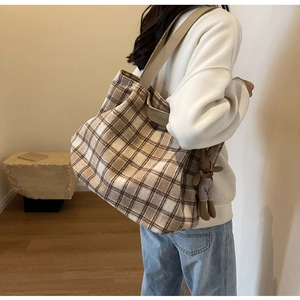 Detail of wool tote bag with brown plaid pattern and cute rabbit charm for daily use