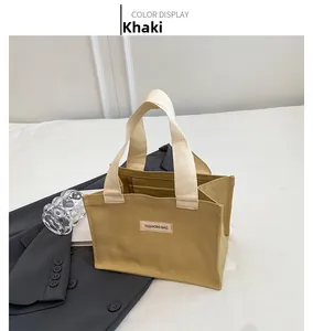 Vue de dessus d'un sac cabas en toile kaki avec anses crème sur un blazer gris