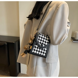 Detail view of checkerboard crossbody phone bag with cute bunny doll charm accessory
