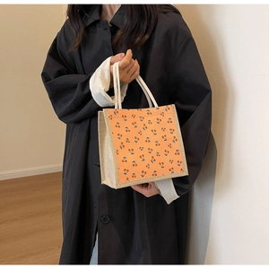 Close-up of corduroy tote bag featuring orange cherry pattern and white rope handles