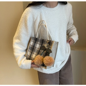 Detailed close-up of retro plaid canvas handbag with a cute plush cherry charm accessory