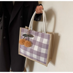 Close-up of purple checkered linen tote bag with rope handle and plush cherry charm detail