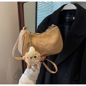 Détail du sac à bandoulière beige à motif crocodile avec broderie papillon et bijou de sac
