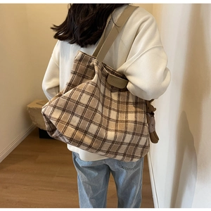 Close-up of brown checkered wool tote bag with leather strap and cute bear charm