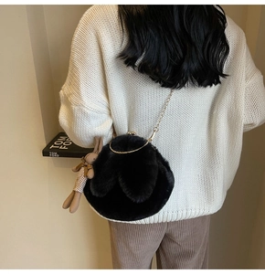 Detail of black plush bunny crossbody bag with gold chain and cute rabbit charm pendant