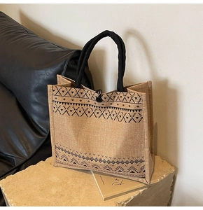 Detail of jute tote bag featuring black geometric wave prints and round black handles