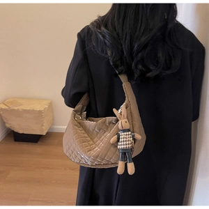Sac à bandoulière matelassé marron en forme de croissant avec un charm lapin sur le modèle
