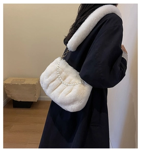 Detail of white plush cloud bag with pearl chain strap on black coat