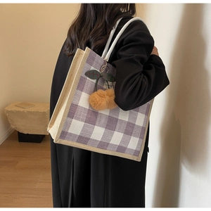 Close-up of a large purple checkered linen tote bag with a decorative cherry charm